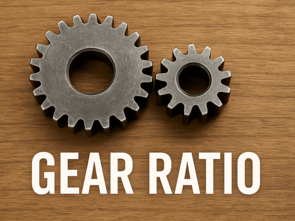 Ahşap zemin üzerine yerleştirilmiş, birbirine geçmiş iki gerçek metal dişliyi gösteren bir fotoğraf.