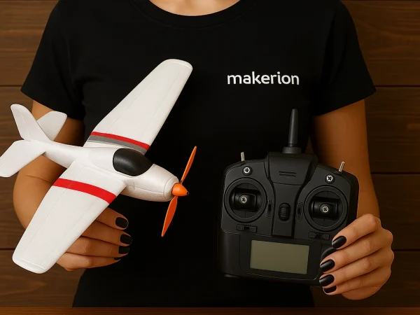 Ahşap arka plan önünde, siyah ojeli tırnaklara sahip bir kadın, siyah "makerion" tişört giyerek ellerinde bir RC uçak tutuyor.